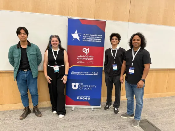 Students and Dr. MBarki standing around the QatarDebate sign