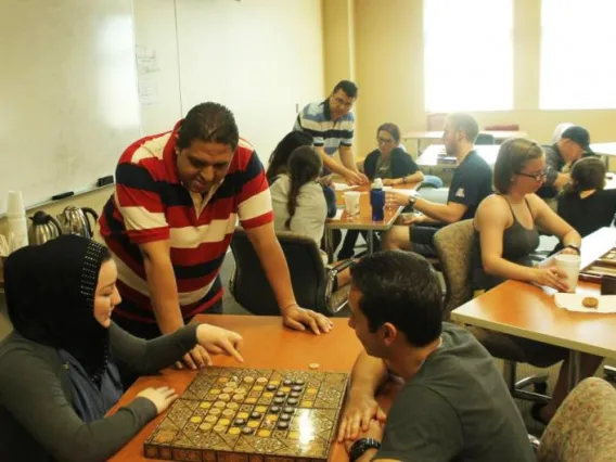 two people playing a board game as one man watches