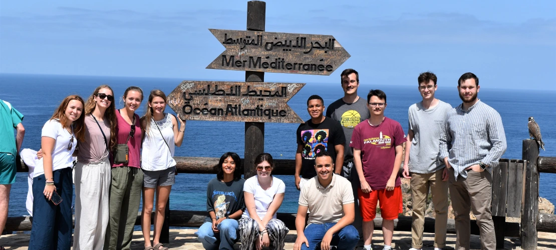 A group of students standing in front of the sea.
